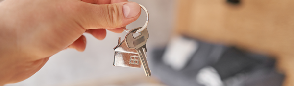 Une personne porte une clé avec un appartement en fond.