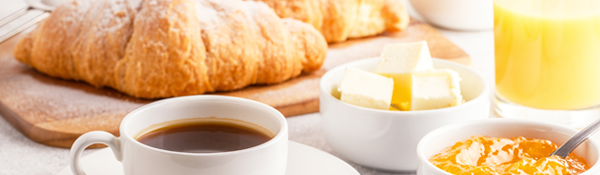 Petit déjeuner composé de croissants, beurre, confiture, café et jus d'orange sur une table